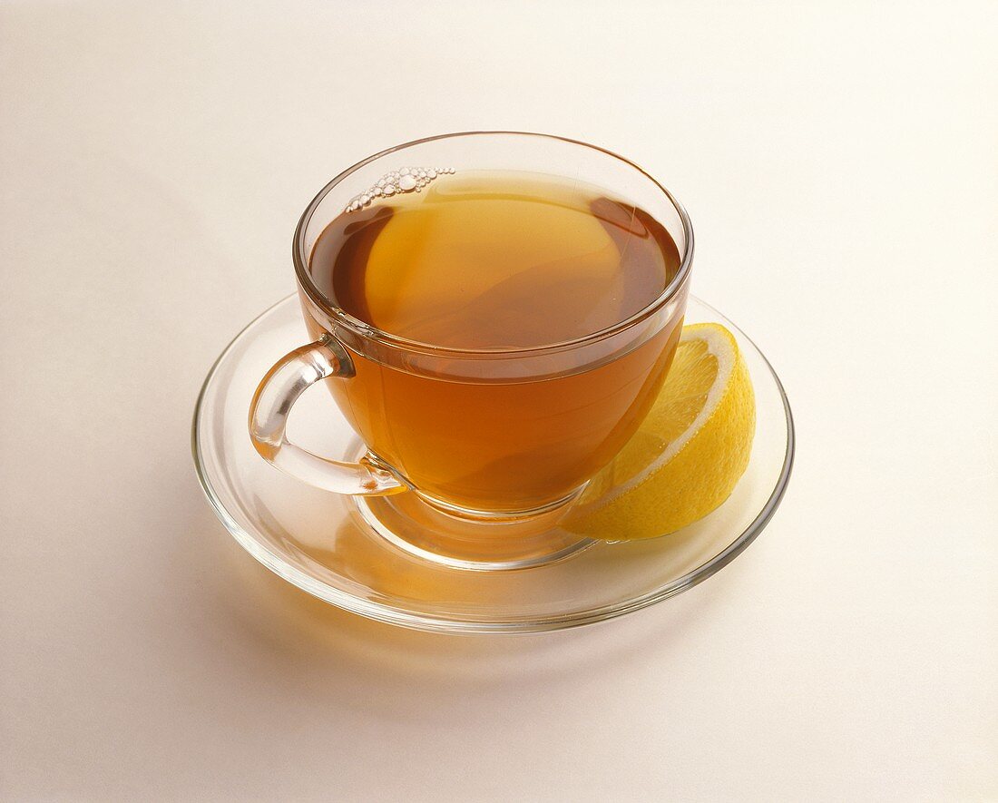 Tee in Tasse aus Glas mit Zitronenspalte