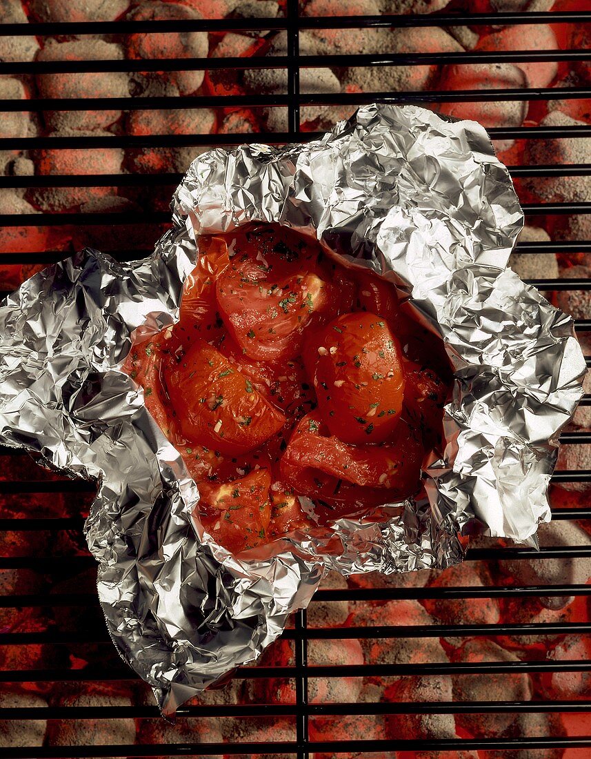 Tomaten mit Knoblauch und Petersilie in Folie auf dem Grill