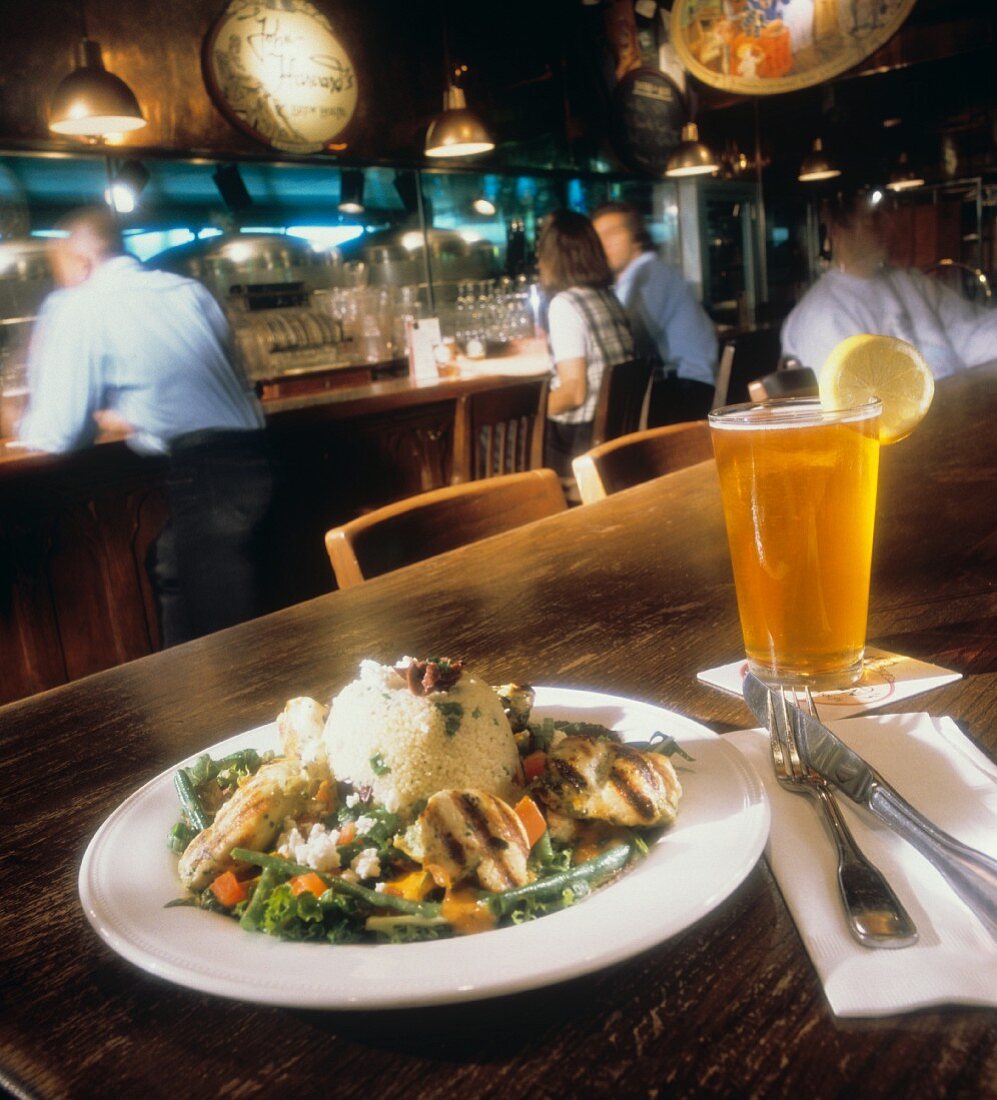 Hähnchen mit Couscous & Bier auf Tisch in einem Pub