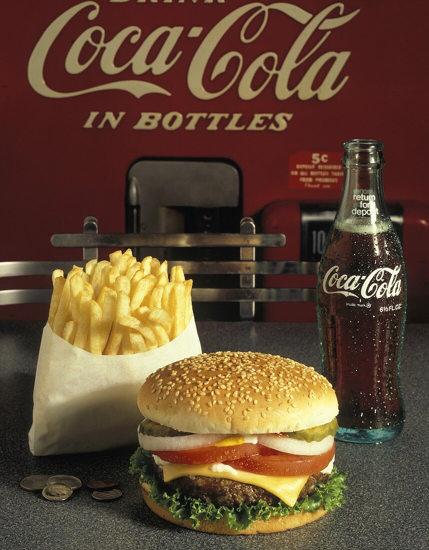 Cheeseburger vor einer Tüte Pommes frites und Coca Cola