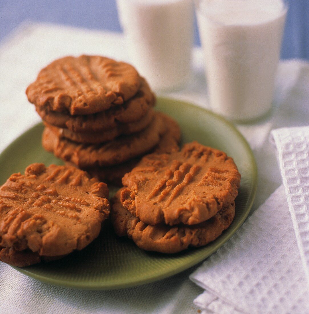 Erdnussbutterkekse auf Teller vor zwei Milchgläsern