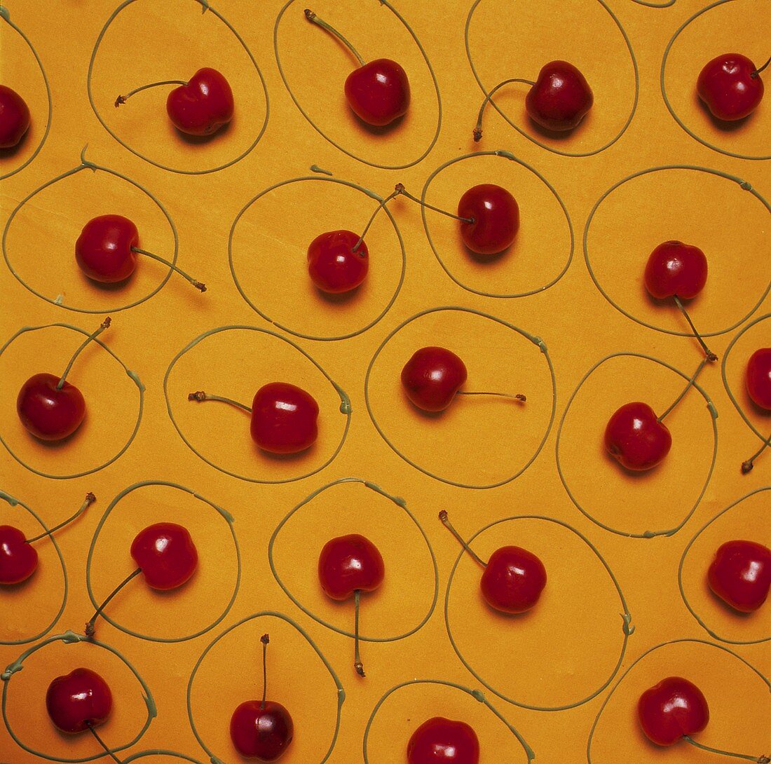 Einzelne frische Kirschen in Kreisen auf gelbem Untergrund