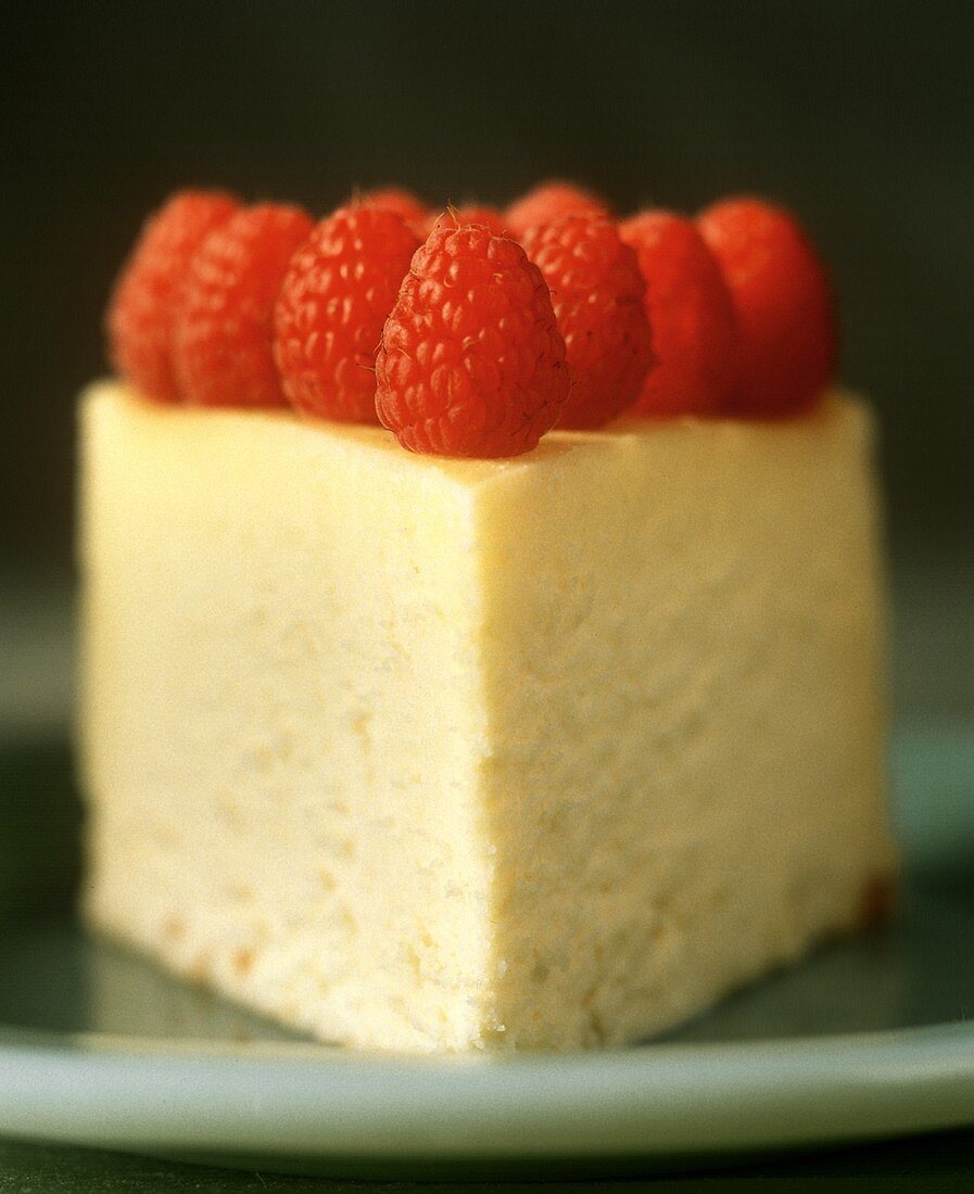 Ein Stück Käsekuchen mit Himbeeren dekoriert