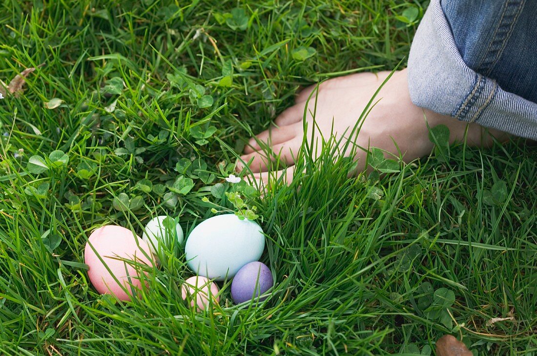 Easter eggs in the grass next to a bare foot