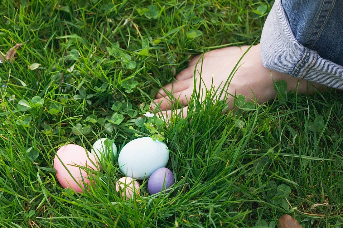 Ostereier im Gras neben nacktem Fuss