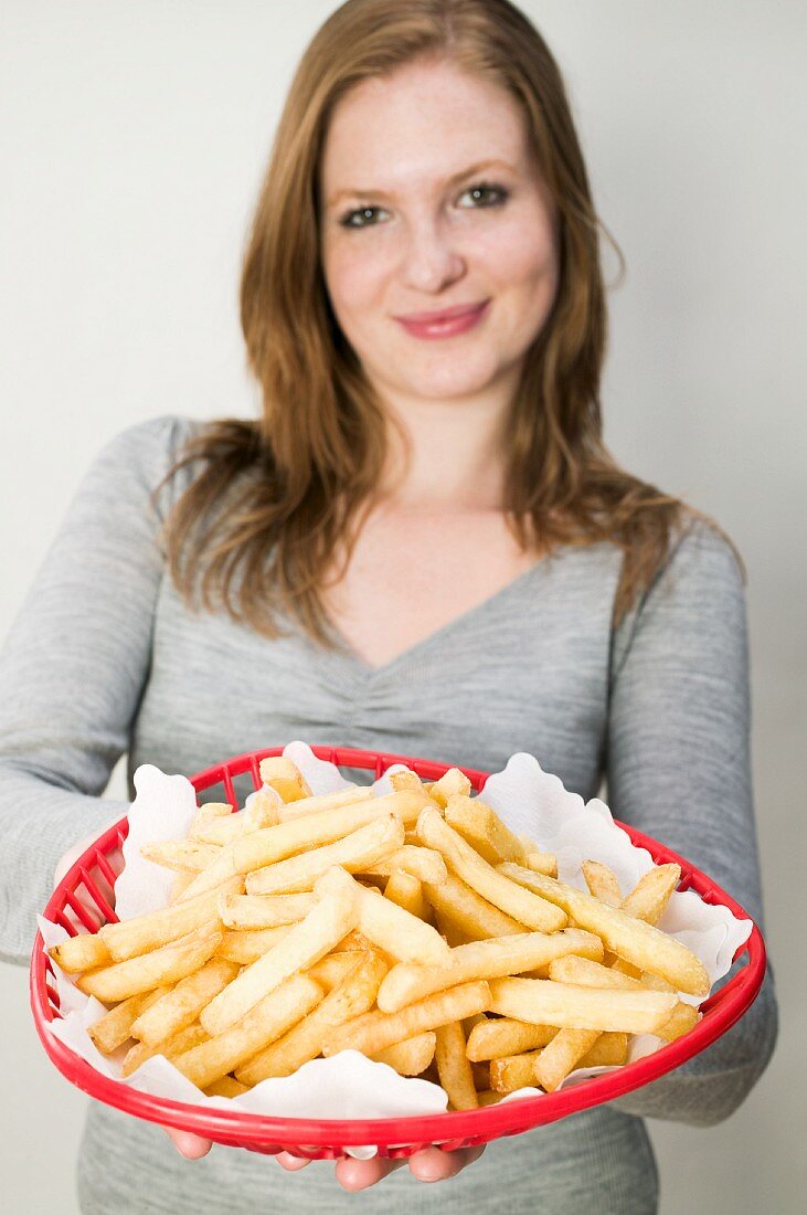 A young woman holding a red basket of chips