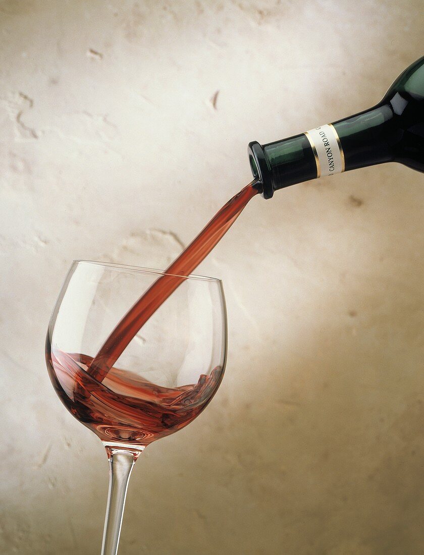 Rotwein aus Flasche in ein Glas einschenken