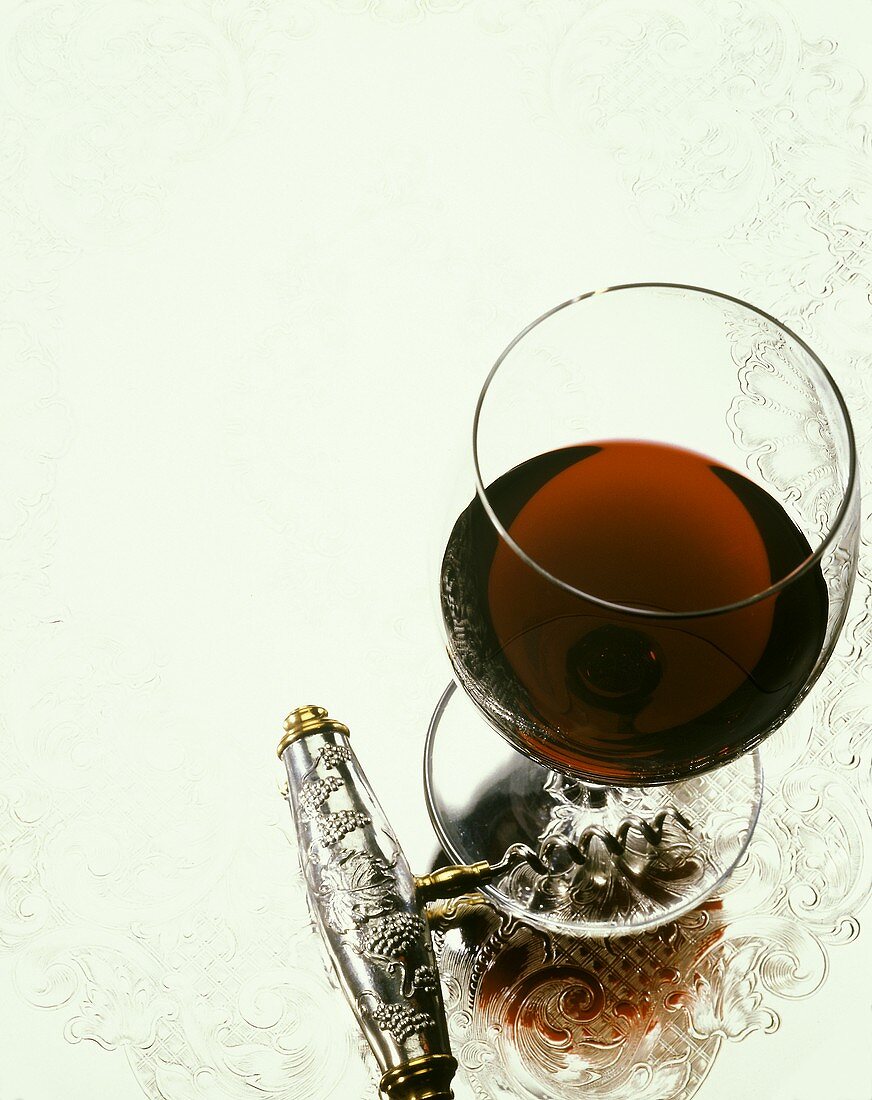 Ein Glas Rotwein und ein silberner Korkenzieher