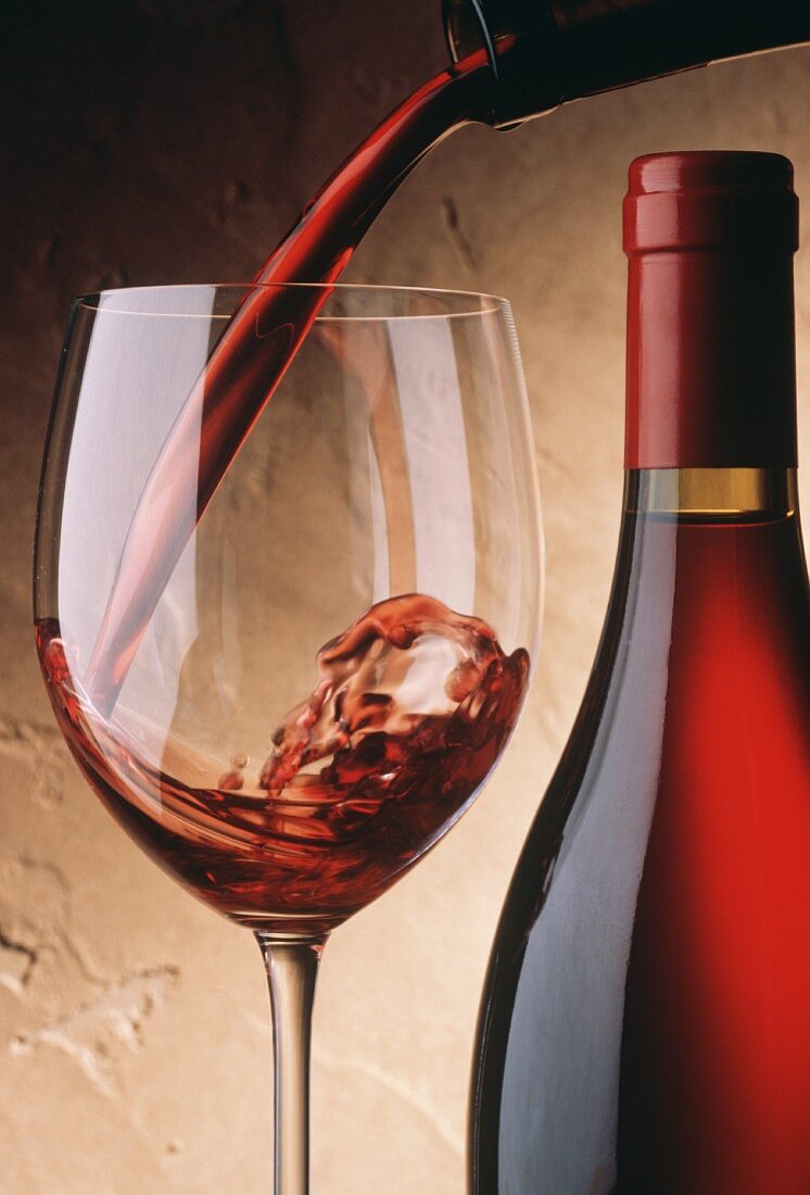Rotwein aus Flasche in ein Glas einschenken