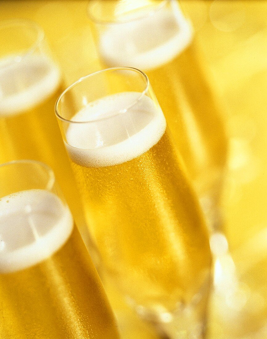 Mehrere gefüllte Champagnergläser in gelbem Licht