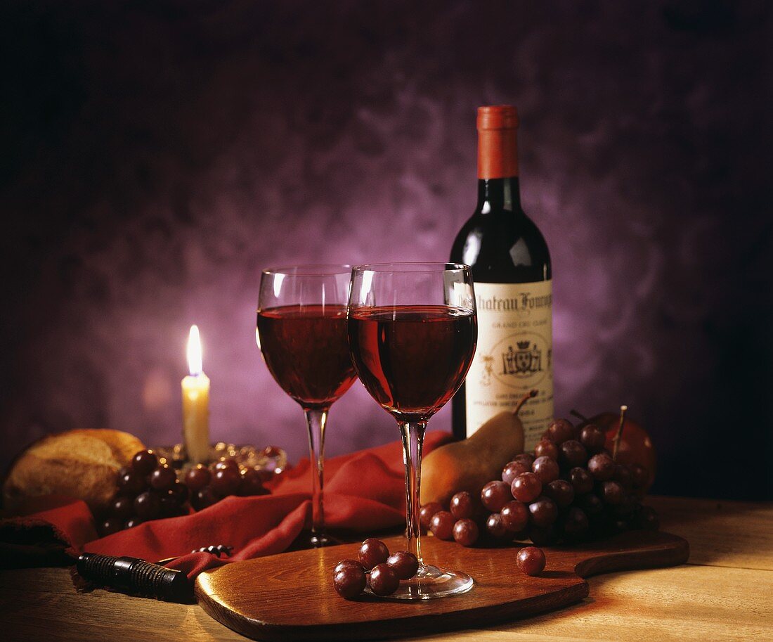 Rotwein und Trauben bei Kerzenlicht