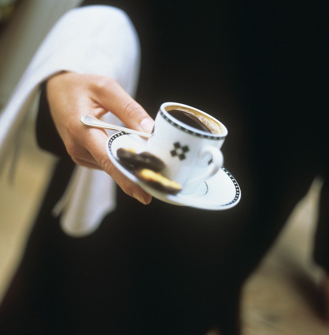 Kellner trägt eine Tasse Kaffee mit Keksen