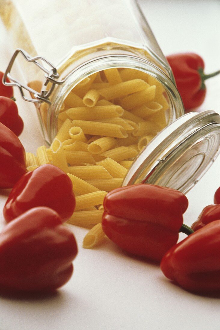 Penne im Glas, umgeben von roten Paprika