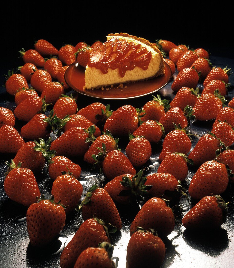 Ein Stück Erdbeer-Käse-Kuchen, umgeben von Erdbeeren