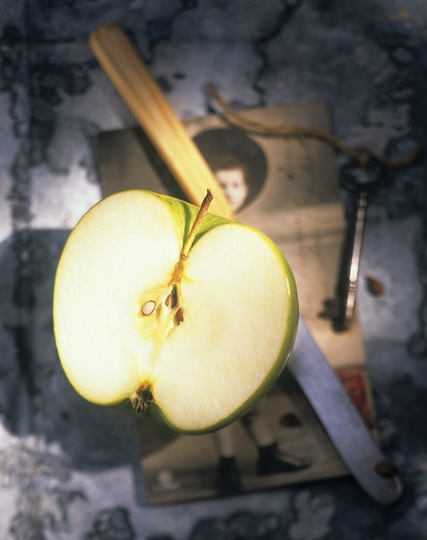 Halbierter Apfel mit Messer auf alter Postkarte