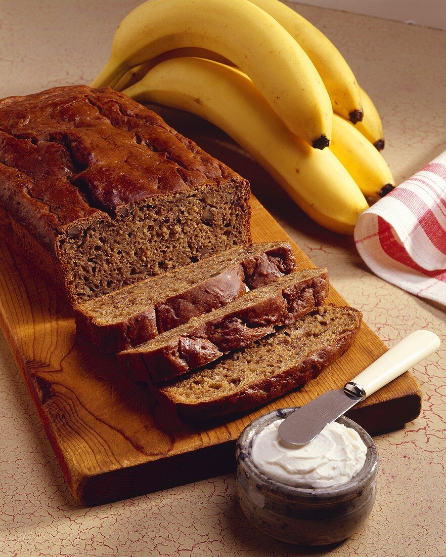 A Partially Sliced Loaf of Banana Bread; Cream Cheese