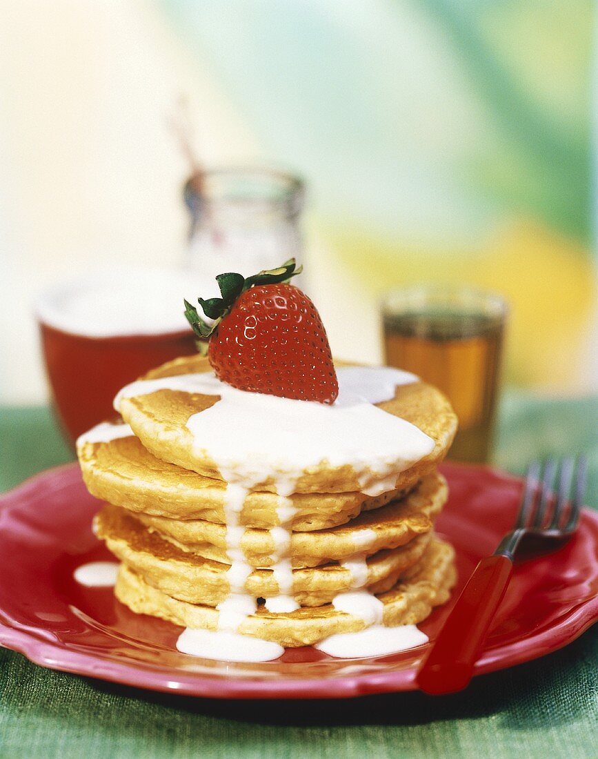 A Stack of Oatmeal Pancakes with Yogurt Sauce and a Strawberry