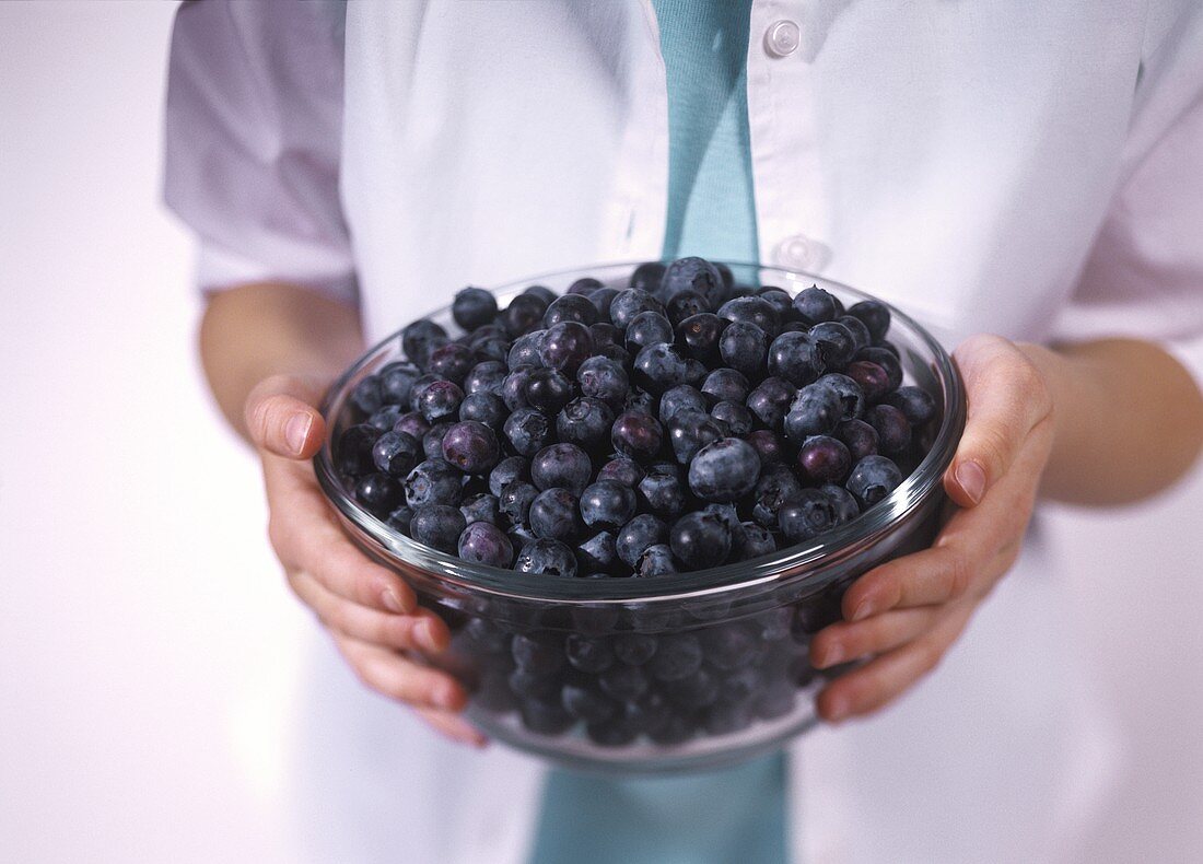 Hände halten Schüssel mit freischen Heidelbeeren