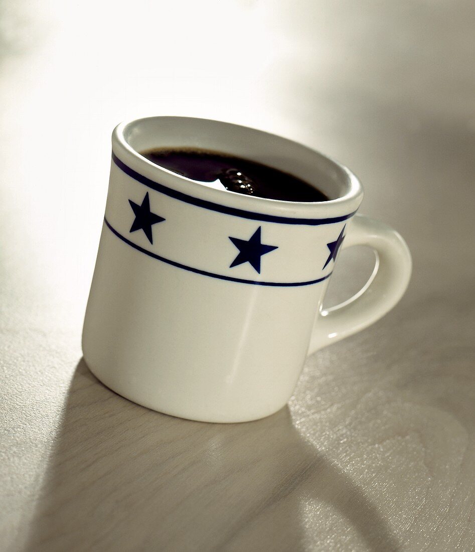 Schwarzer Kaffee in grosser Tasse mit blauen Sternen