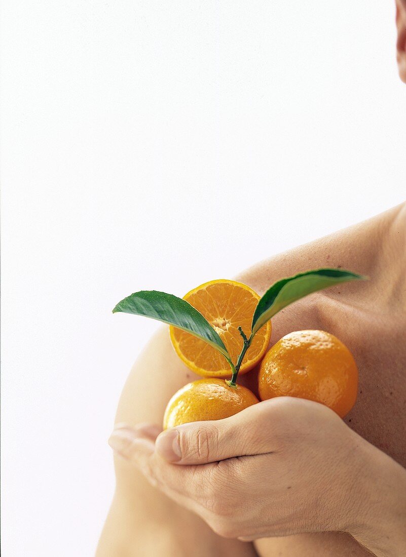 Kraft durch Vitamine: Mann hält Mandarinen an seiner Schulter