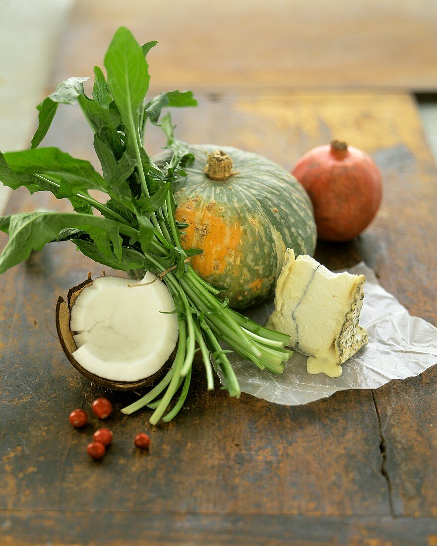 Stillleben mit Kürbis, Kokosnuss, Rucola, Käse und Granatapfel