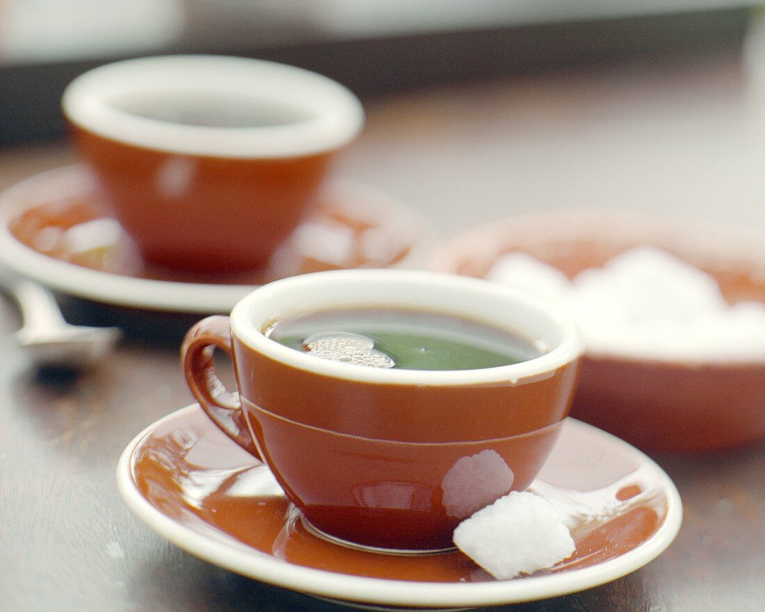 Kaffee in braunen Tassen mit Zuckerwürfeln