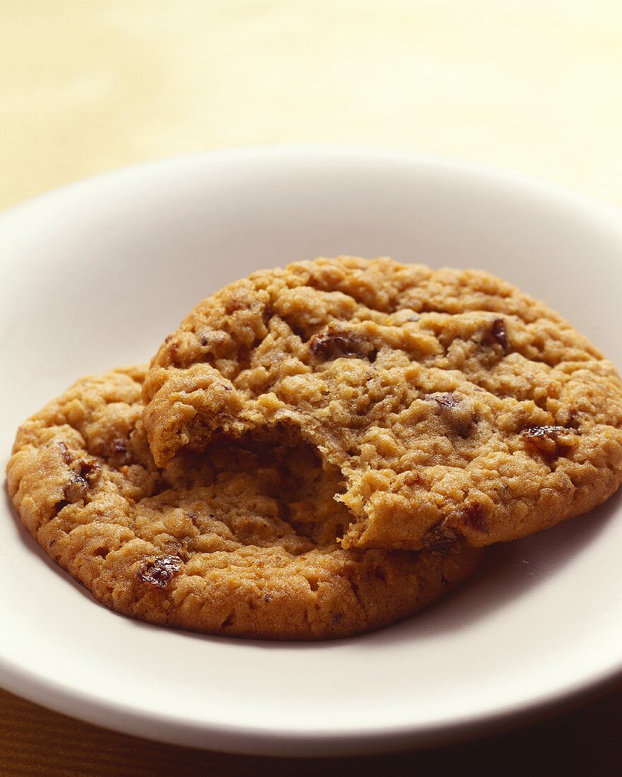 Zwei Hafer-Rosinen-Cookies auf Teller, einer davon angebissen