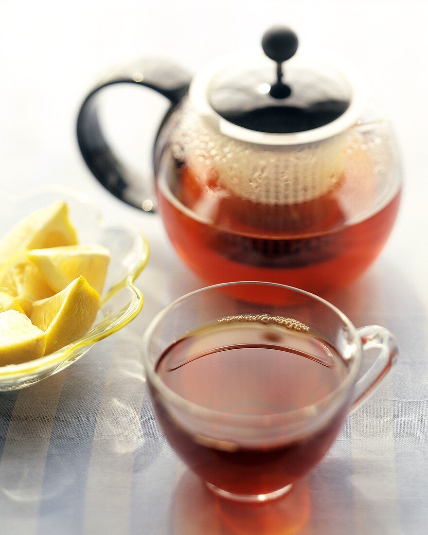 Tea in glass cup and pot and wedge of lemon