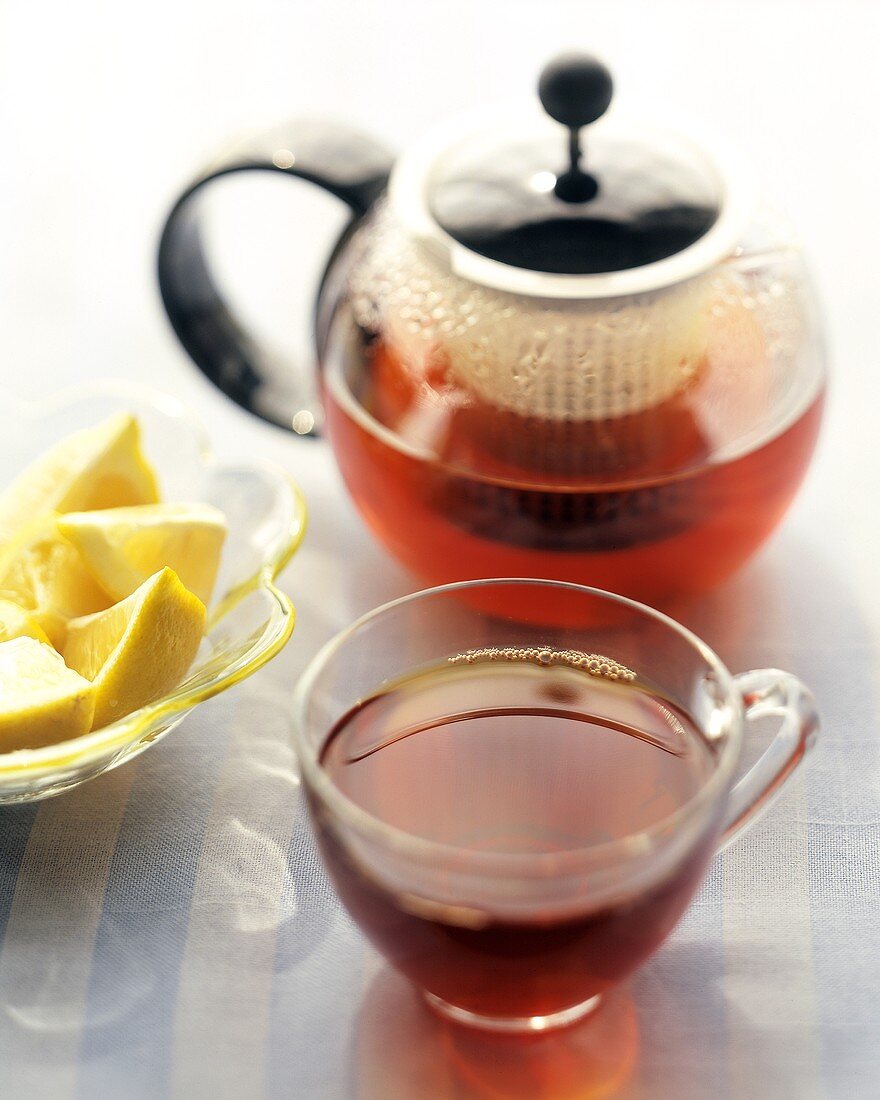 Tee in Glastasse und Kanne und Zitronenschnitze