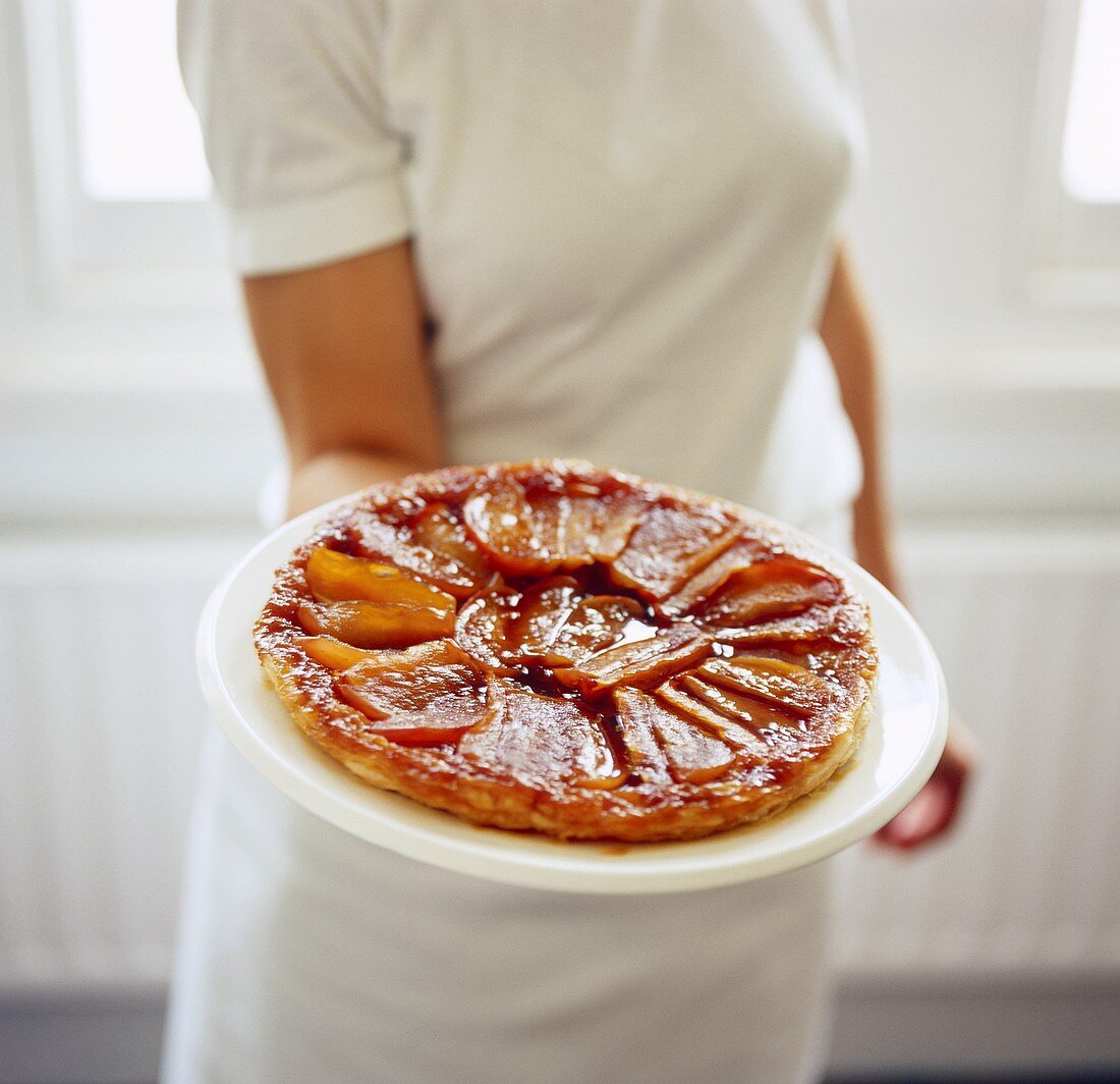 Frau serviert Tarte Tatin auf Teller