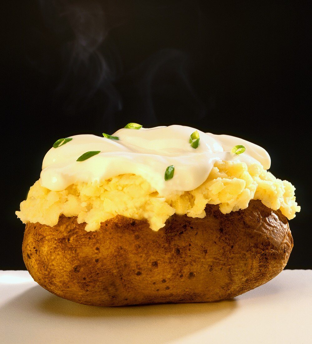 A Steaming Baked Potato with Sour Cream and Chives