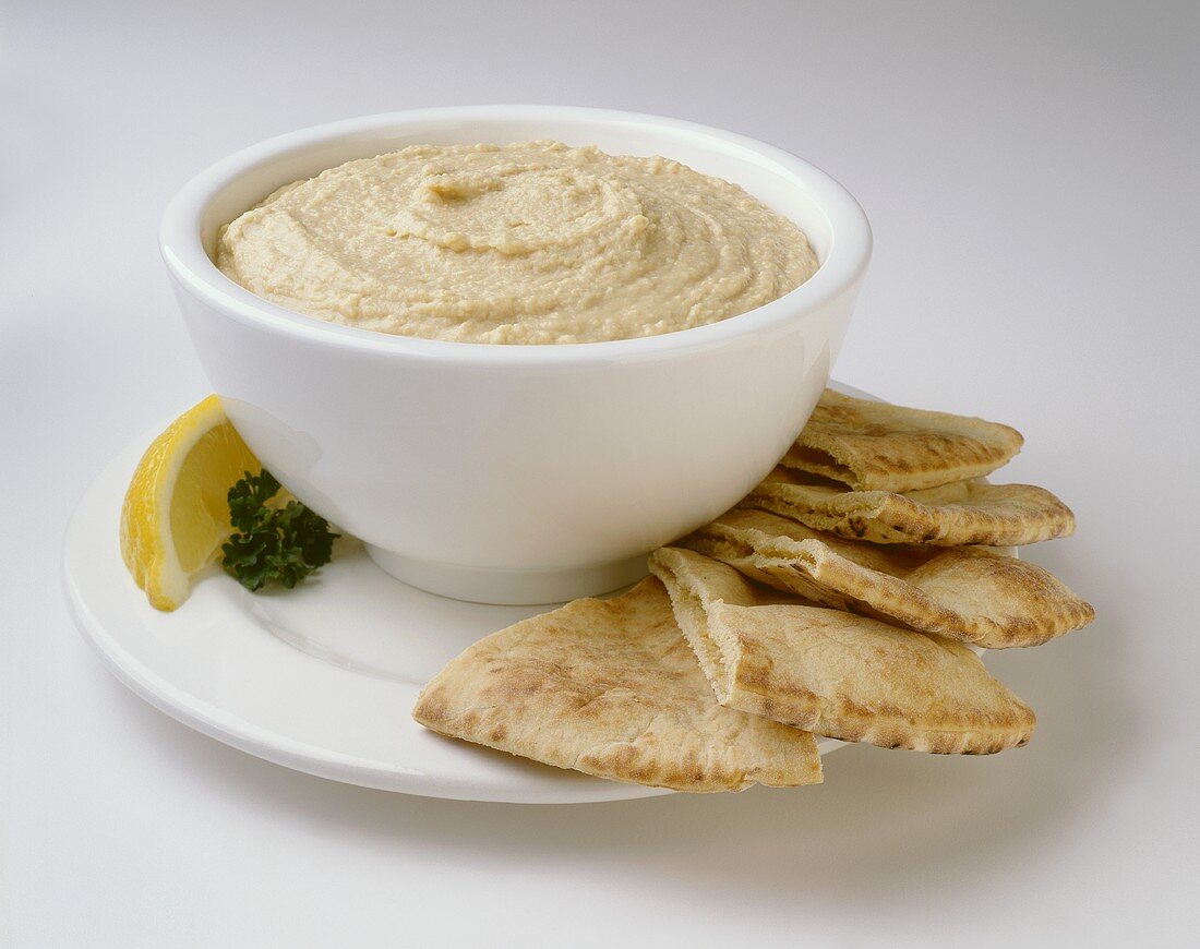 A Bowl of Hummus with Pita Wedges and Lemon