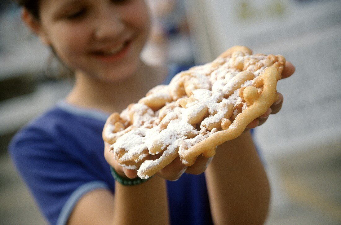 Funnel Cake with Powdered Sugar Held by Smiling Girl