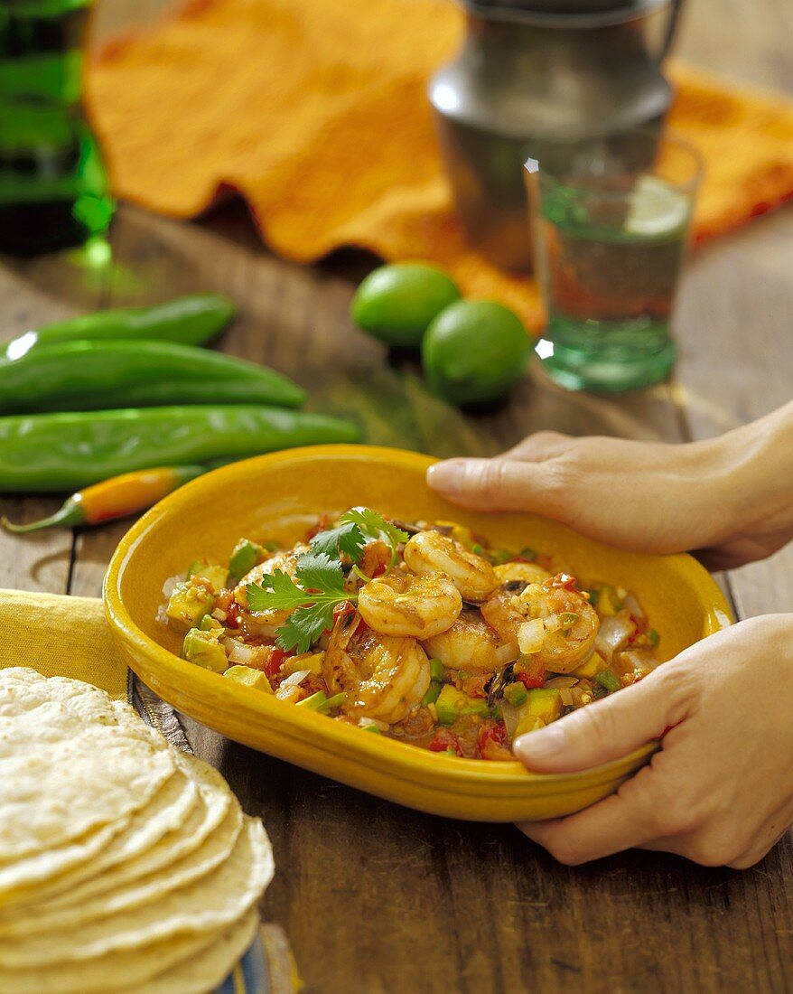 Woman's Hands Holding a Dish of Mexican Style Shrimp