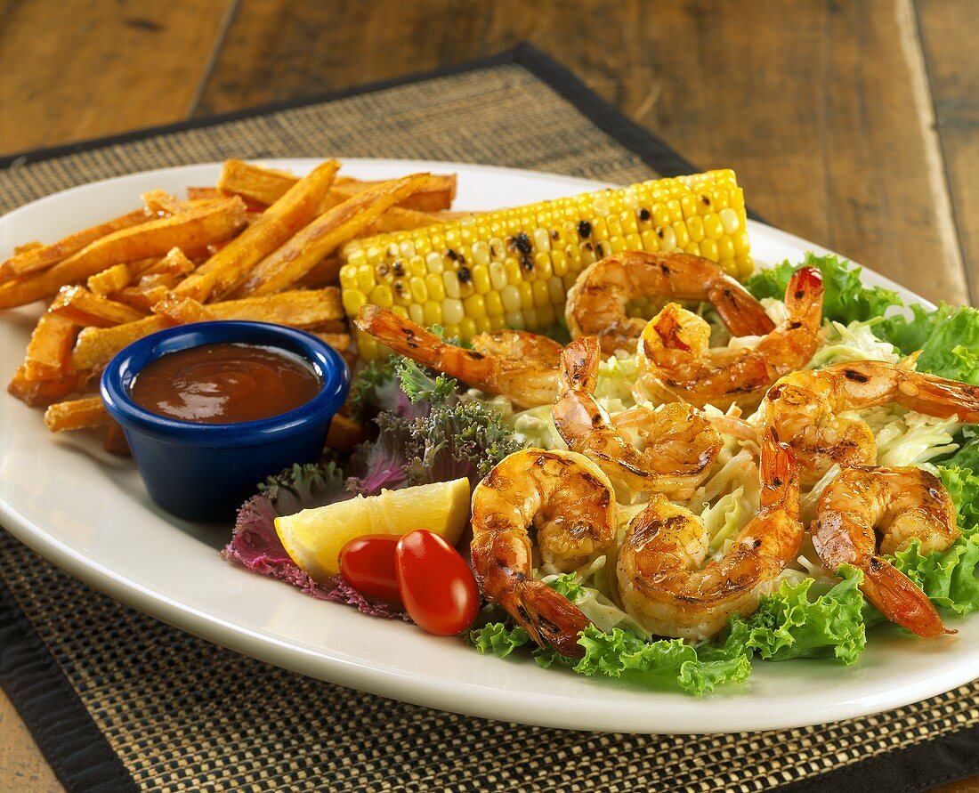 Barbecued shrimps with chips and corncob