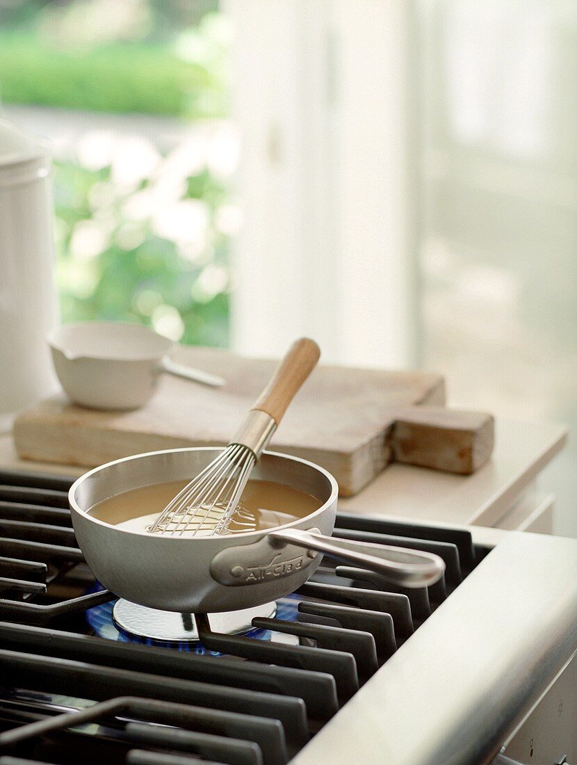 A Saucepan on the Stove with Whisk