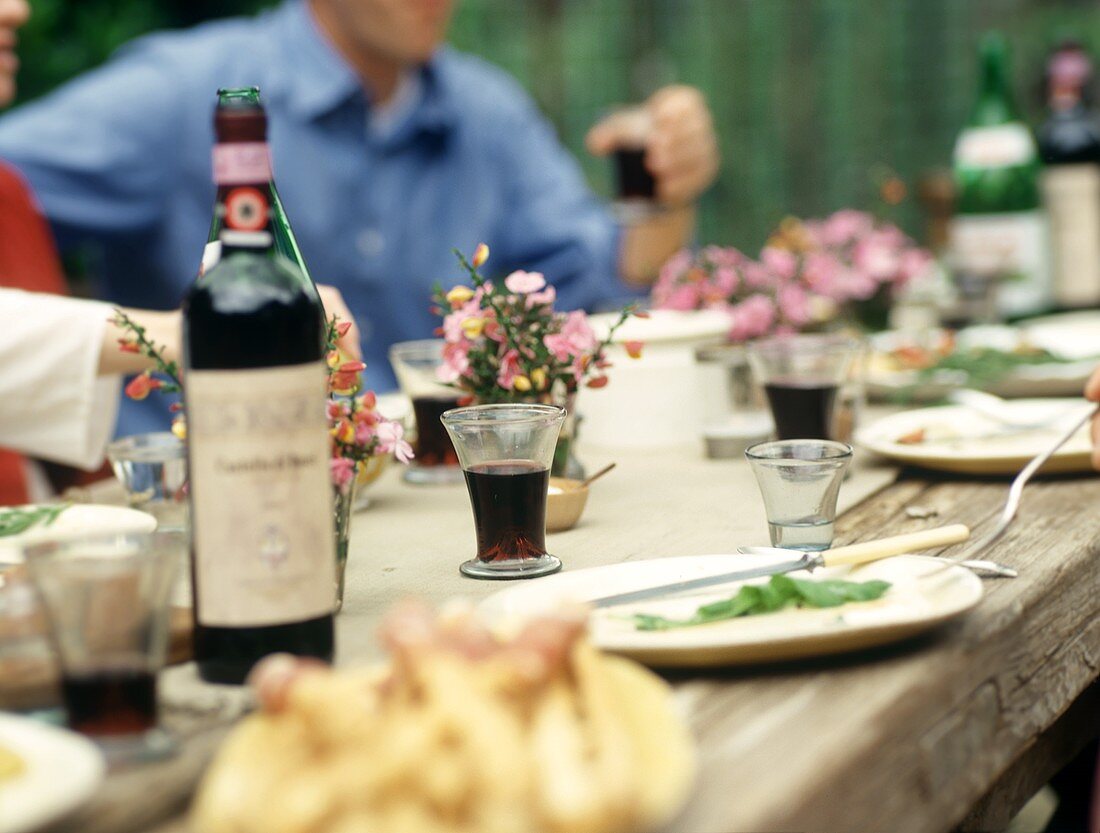 Rustikaler Tisch mit Rotwein im Freien
