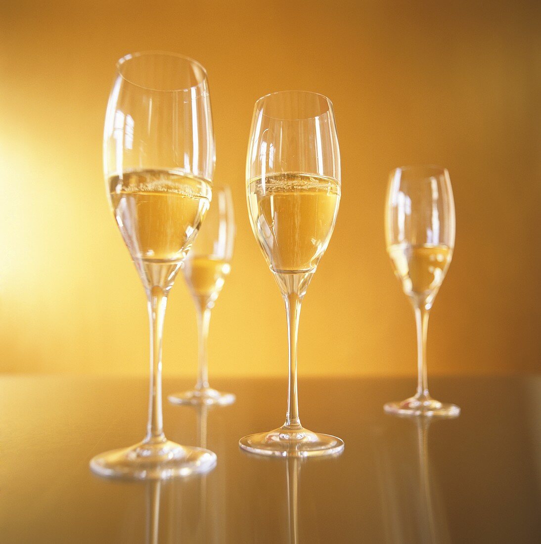 Vier Champagnergläser vor goldenem Hintergrund