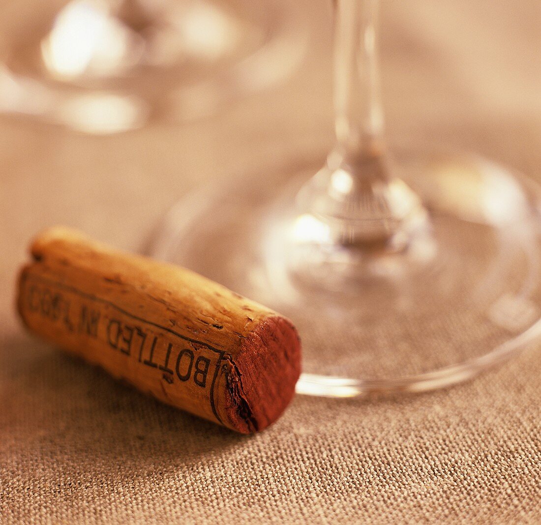 Ein Weinkorken neben dem Stiel eines Weinglases