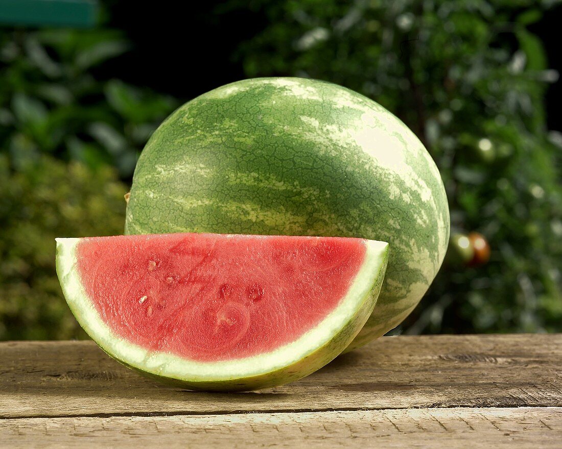 Ganze Wassermelone und Wassermelonenspalte im Freien