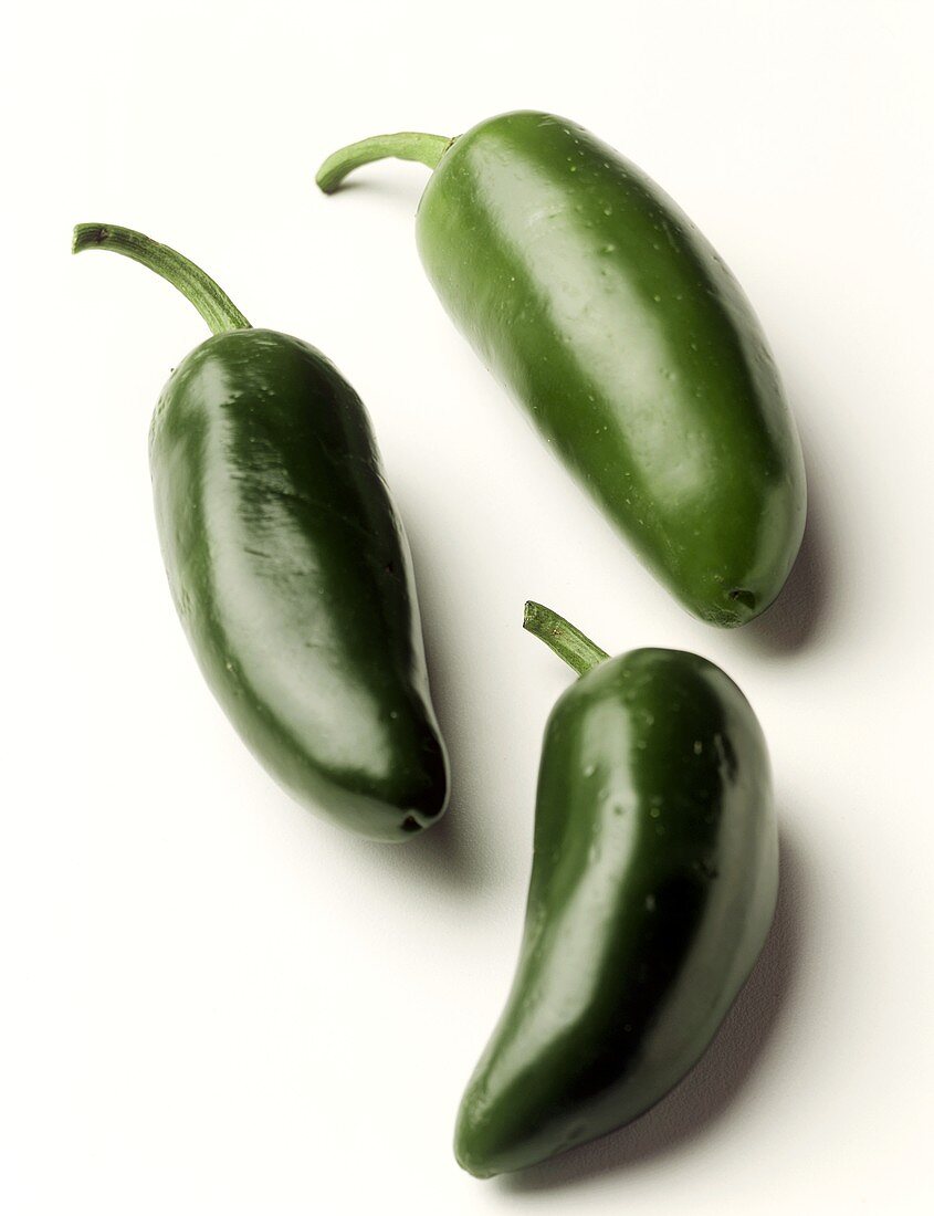 Three green Jalapeño peppers on white background