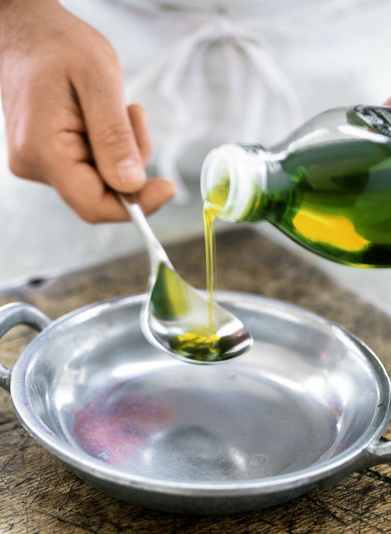 Olivenöl in Löffel gießen