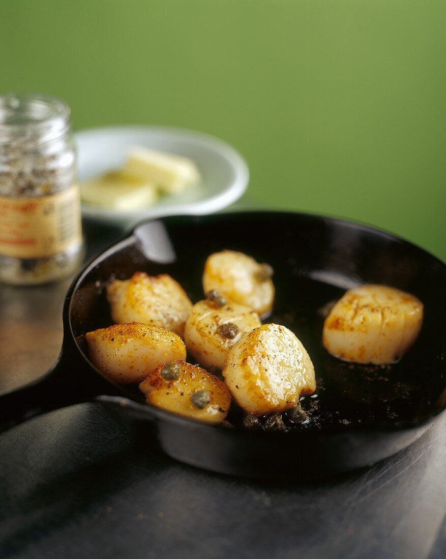 Fried scallops with capers in a pan
