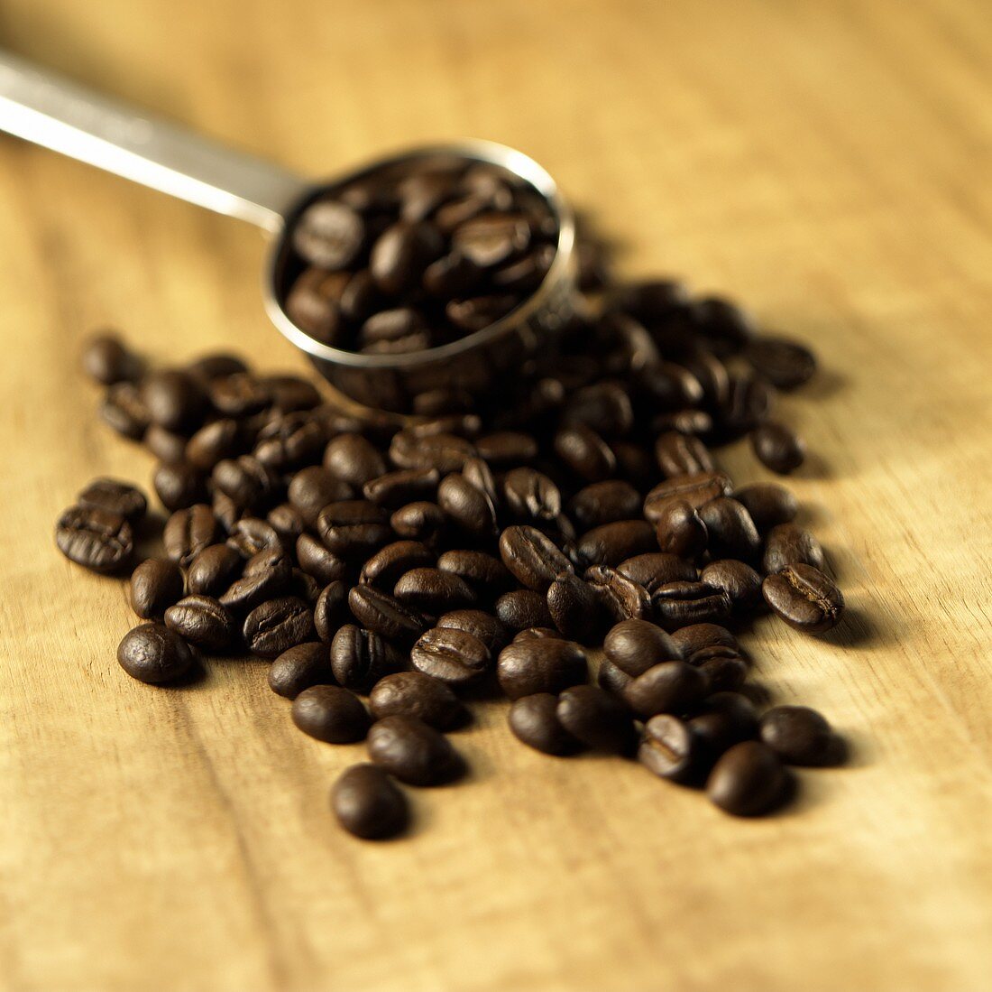 Roasted coffee beans on wooden background, coffee measure