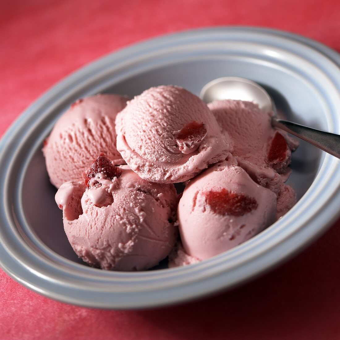 Five scoops of strawberry ice cream in blue bowl