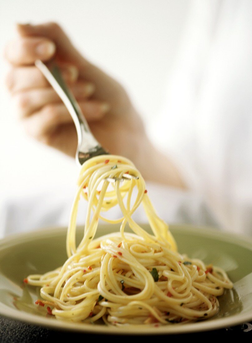 Hand hält Gabel mit Spaghetti