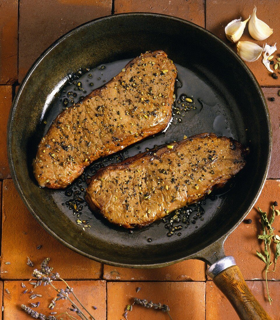 Two Fried Steaks with Garlic in a Frying Pan