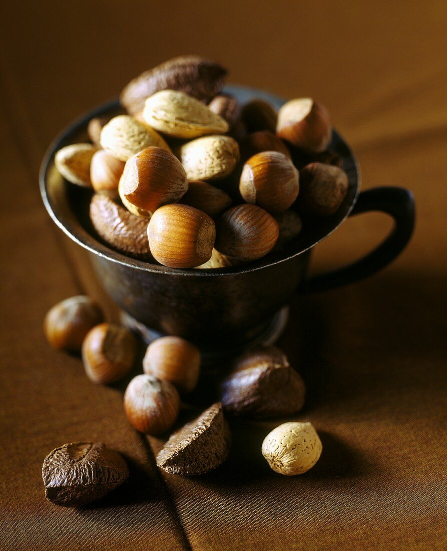 Various nuts in cup on brown background