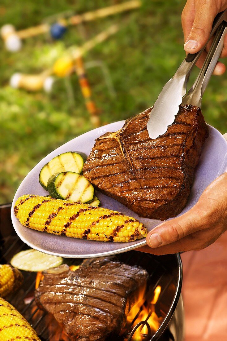 Mixed grill with steak and vegetables above a barbecue