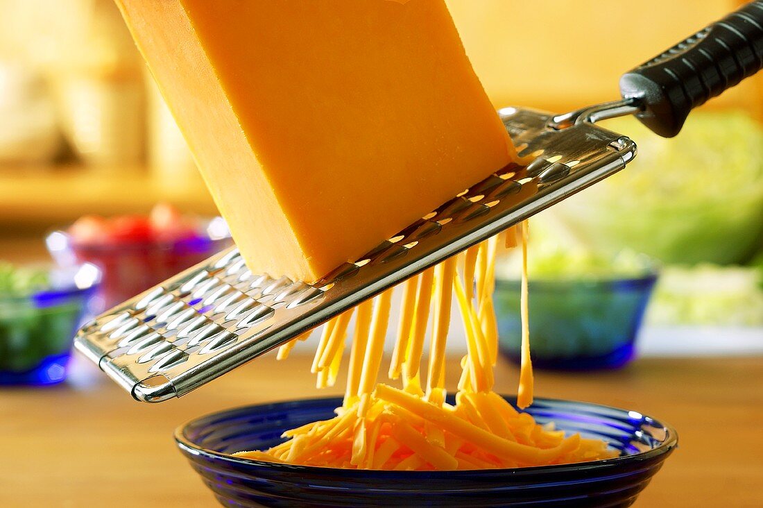 Cheddar being grated with a coarse grater